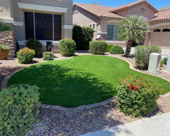 Water-Saving Residential Turf Landscaping Benefits in Arizona Residential front yard with lush, custom-shaped artificial turf and desert landscaping, highlighting water-saving benefits.